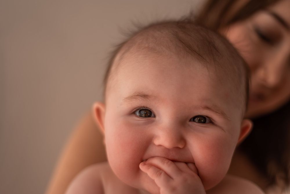 Sweet close-up of a chubby-cheeked baby smiling in warm lighting.