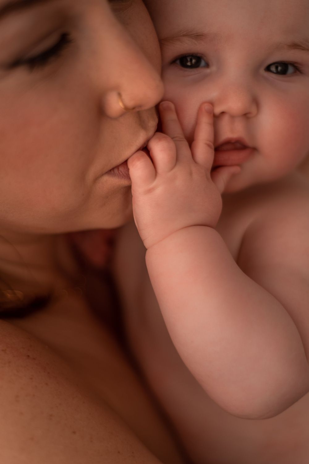 A tender moment between parent and baby as tiny hands touch a loving kiss.