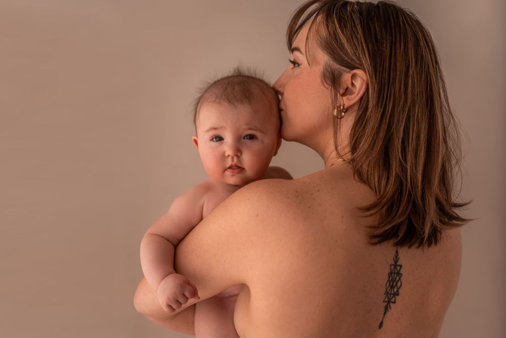 Artistic motherhood portrait showing intimate moment between parent and infant.
