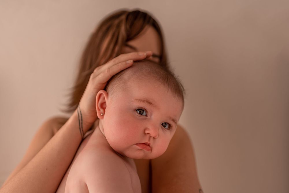 A tender moment captured in warm lighting as a baby rests against a parent's shoulder.