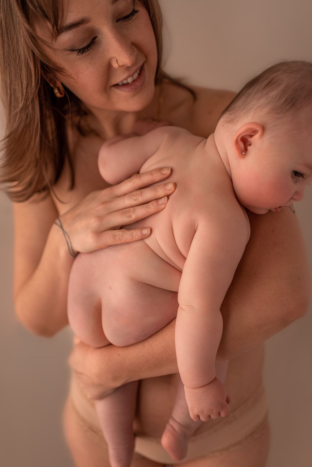 Intimate portrait of maternal bonding with a baby in soft, warm lighting.