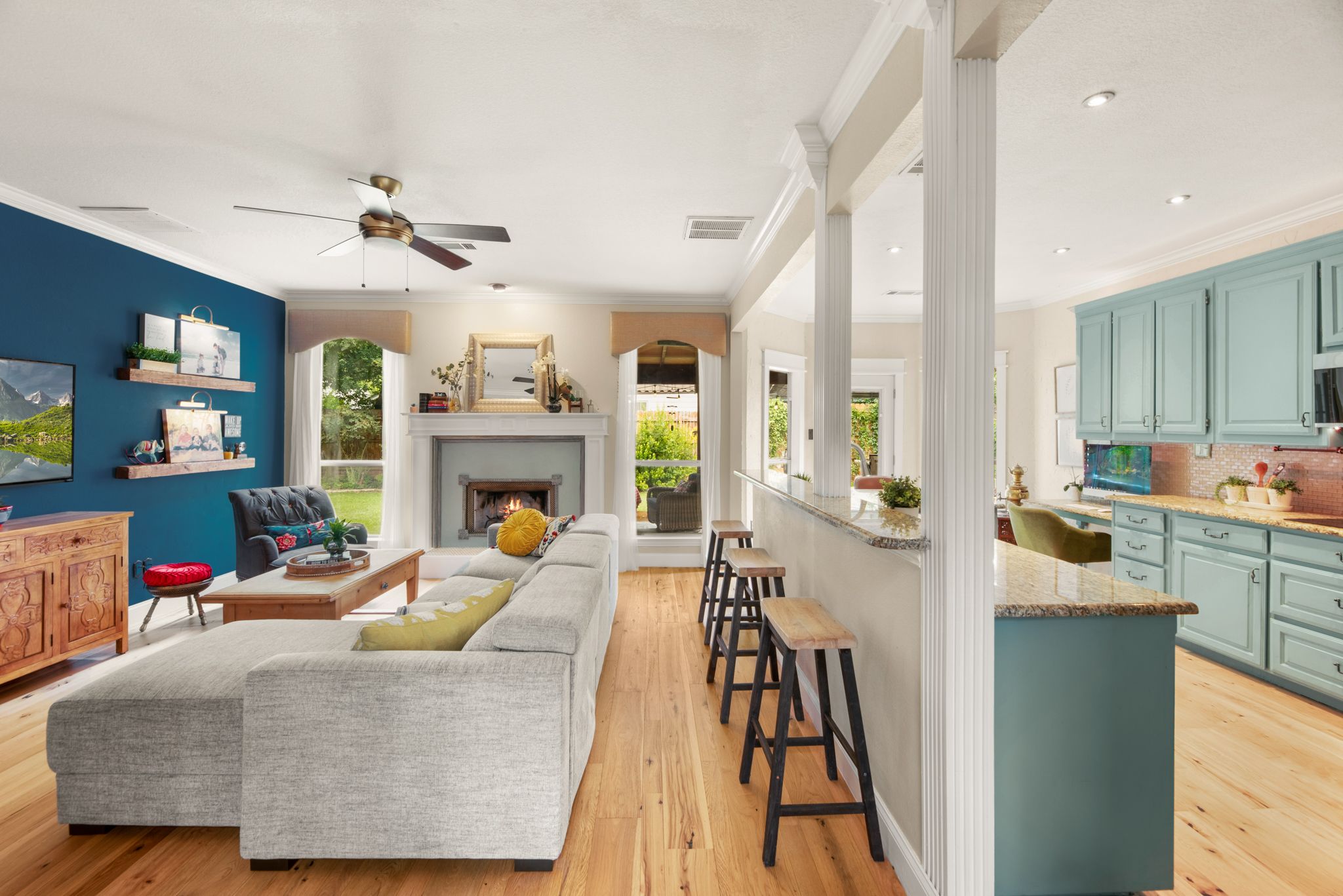 Contemporary living room with light wood flooring, white support columns, and blue accent walls.