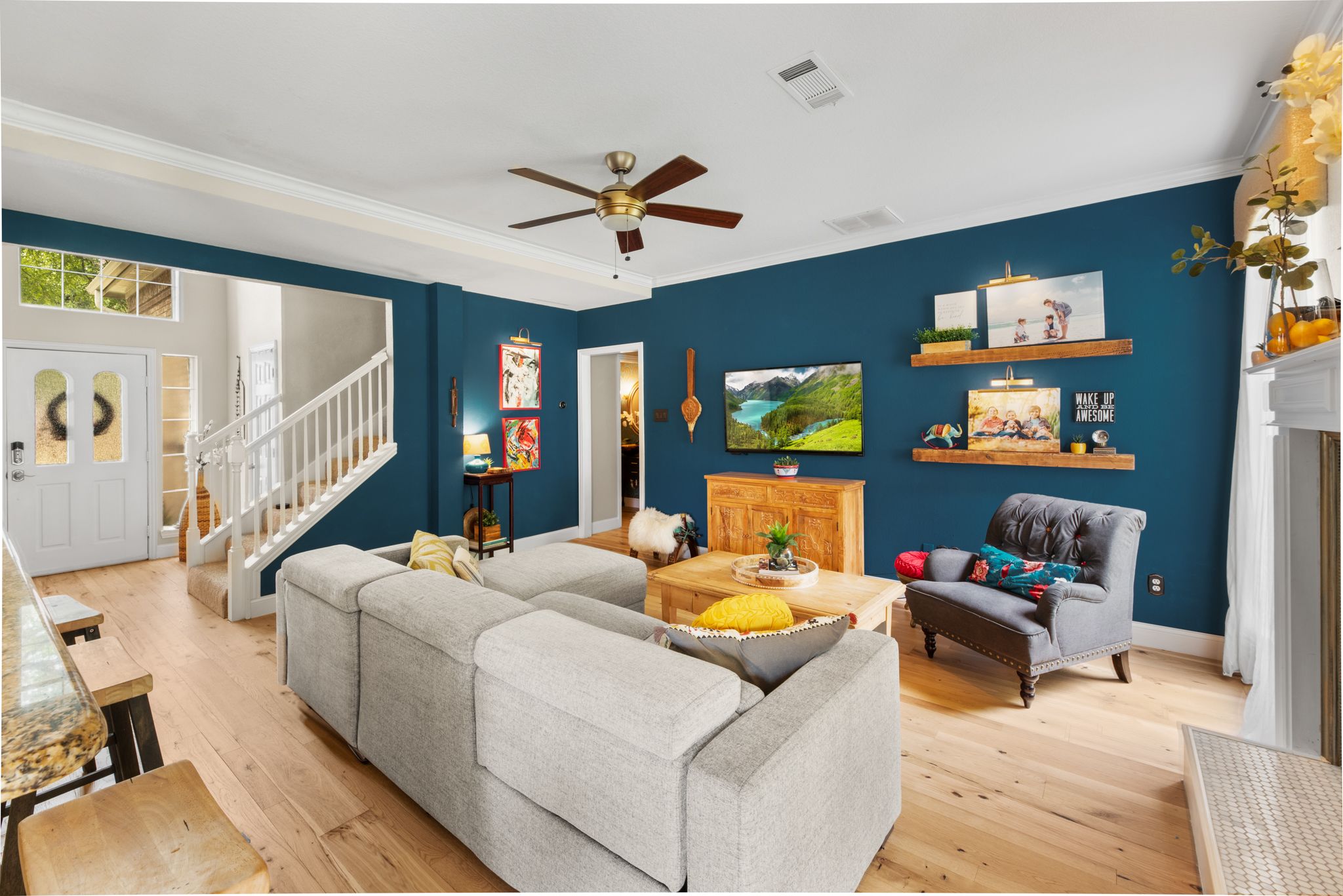Modern living room features light hardwood floors and deep blue accent wall with ledge shelving and floating media unit.