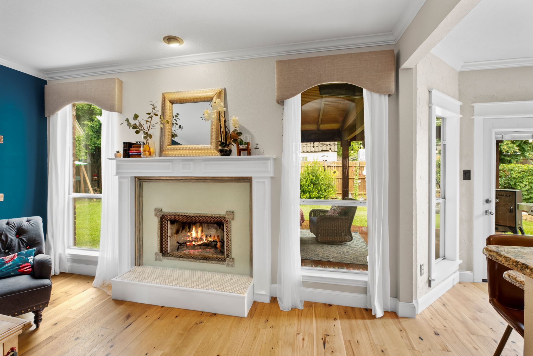 Elegant living room featuring white fireplace, arched doorways, and hardwood floors with views to outdoor space.