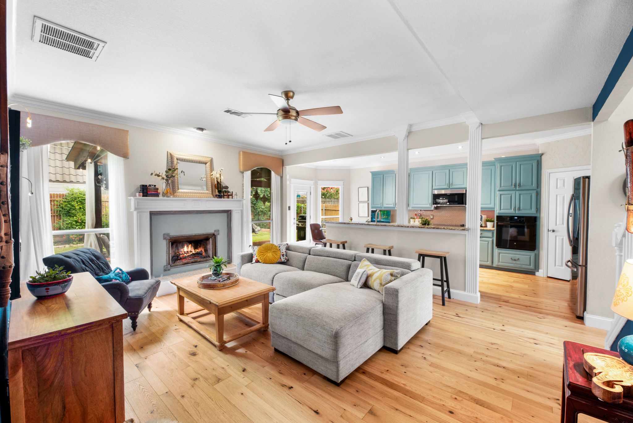 Panoramic view of an open floor plan featuring hardwood floors, white columns, and modern furniture.