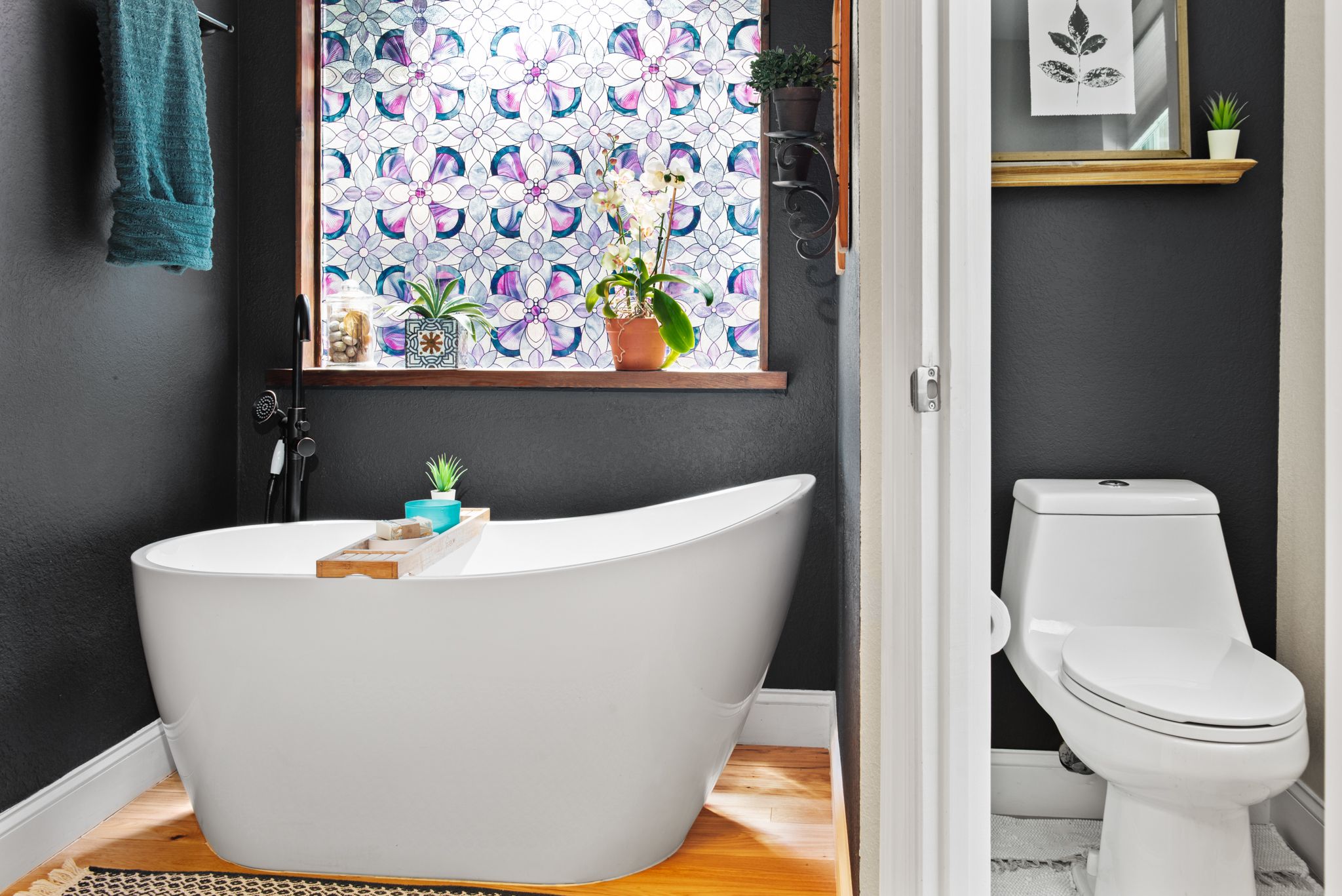 Contemporary bathroom with freestanding soaking tub, patterned window treatment, and gray walls creating a spa-like atmosphere.