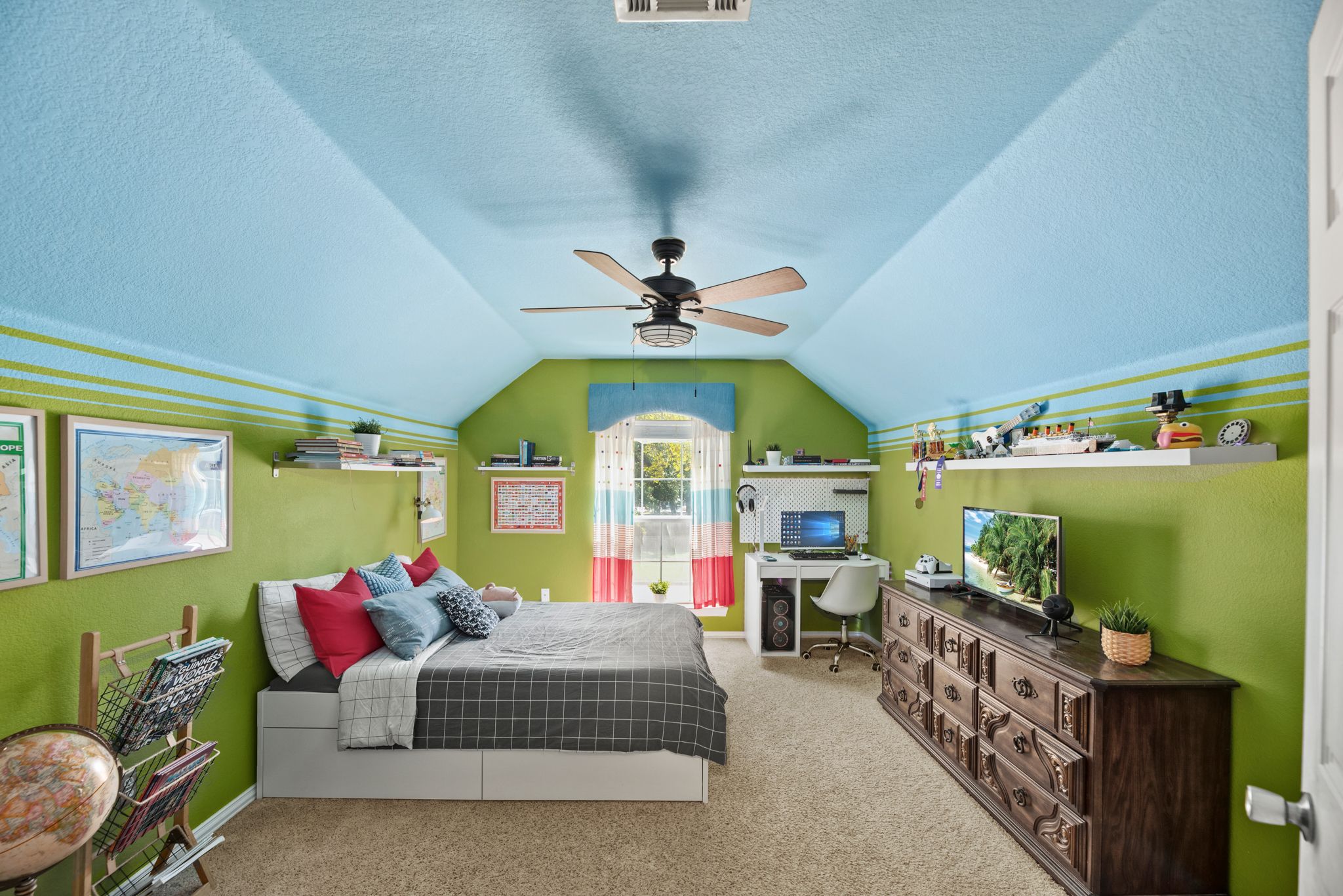 A whimsical child's bedroom with vaulted blue ceiling, green walls, and rustic wooden furniture in a spacious layout.