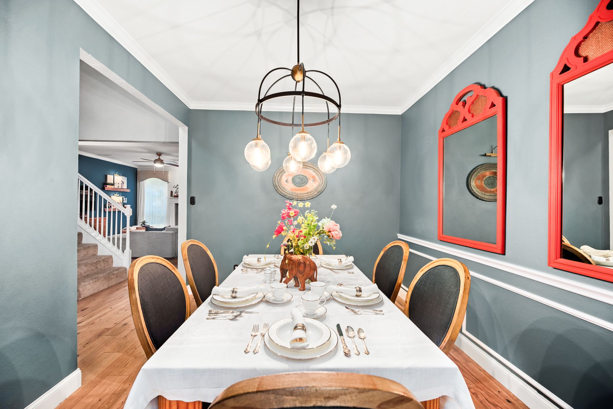 Elegant dining room with navy walls, white trim, pendant lighting and vintage-style decor and furnishings.