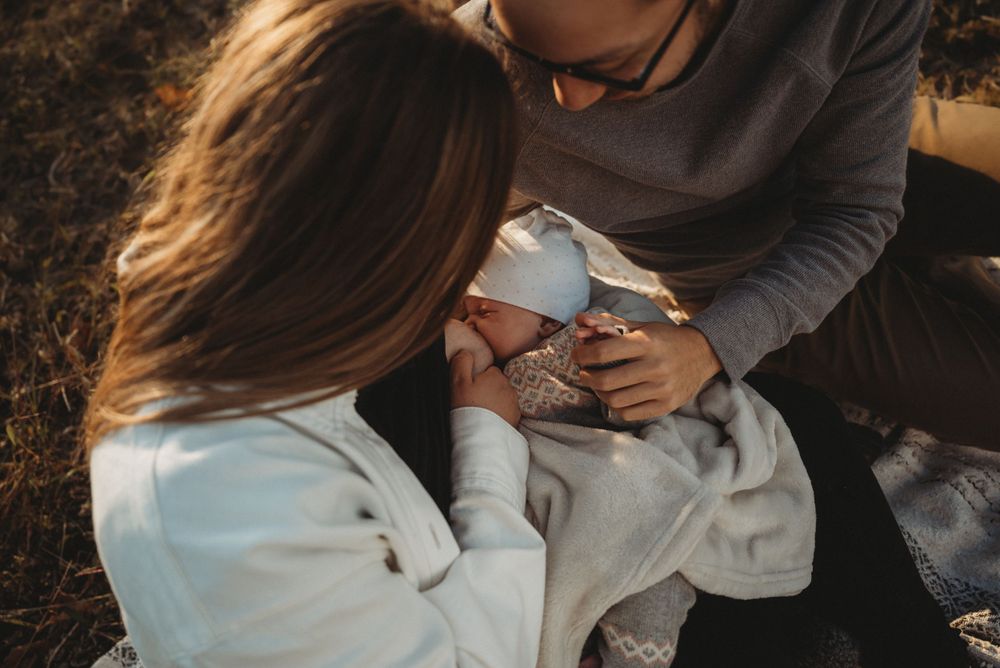 Intimate family moment with newborn baby during outdoor sunset photoshoot.