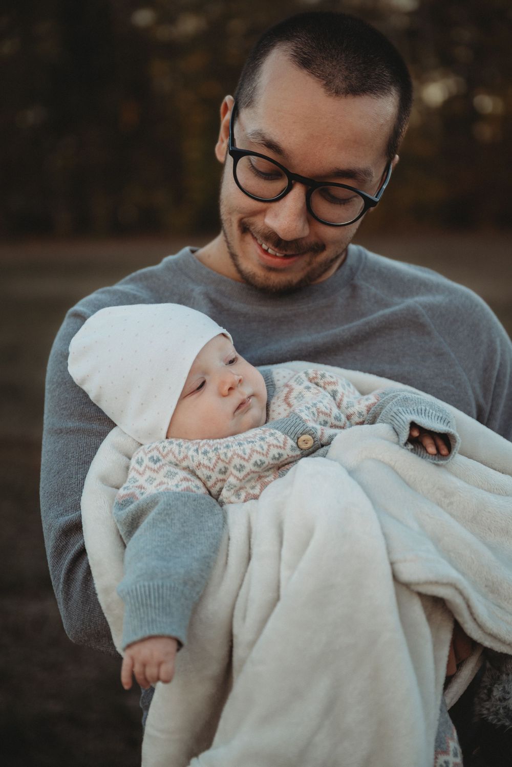 A tender moment between parent and baby wrapped in cozy winter clothes against an autumn backdrop.