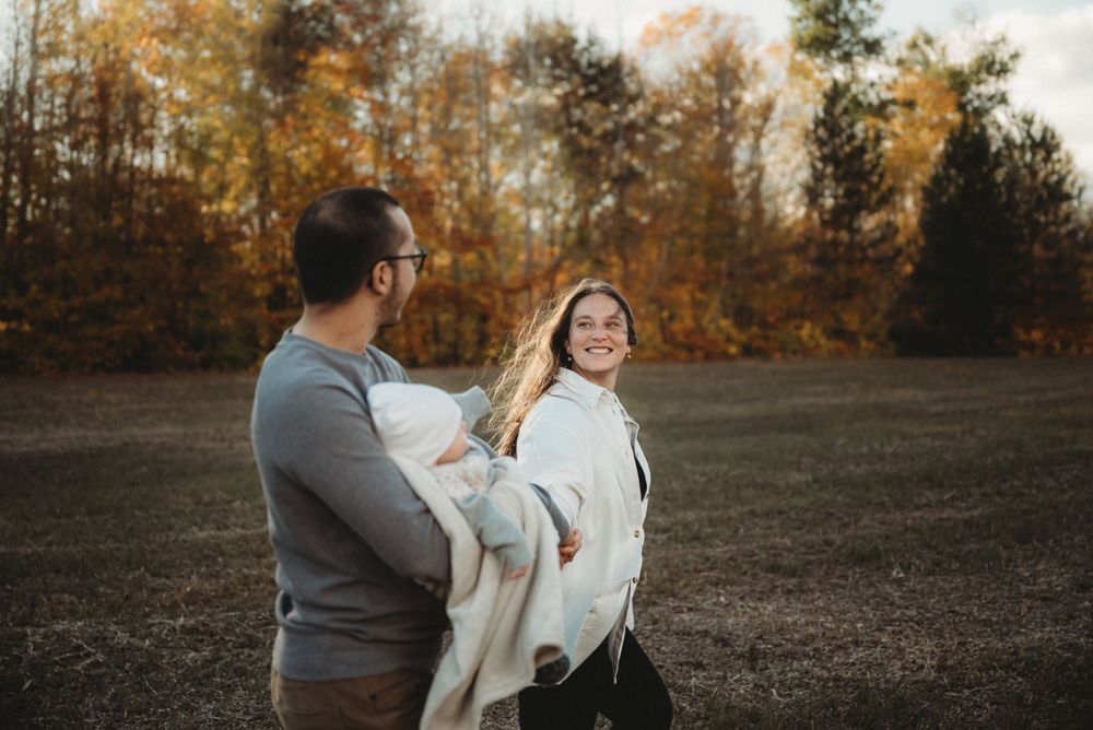 A candid family portrait showing pure joy against a backdrop of fall foliage.