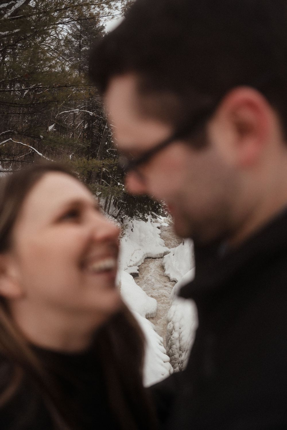 An intimate close-up shot of a couple sharing a laugh during their winter photoshoot.