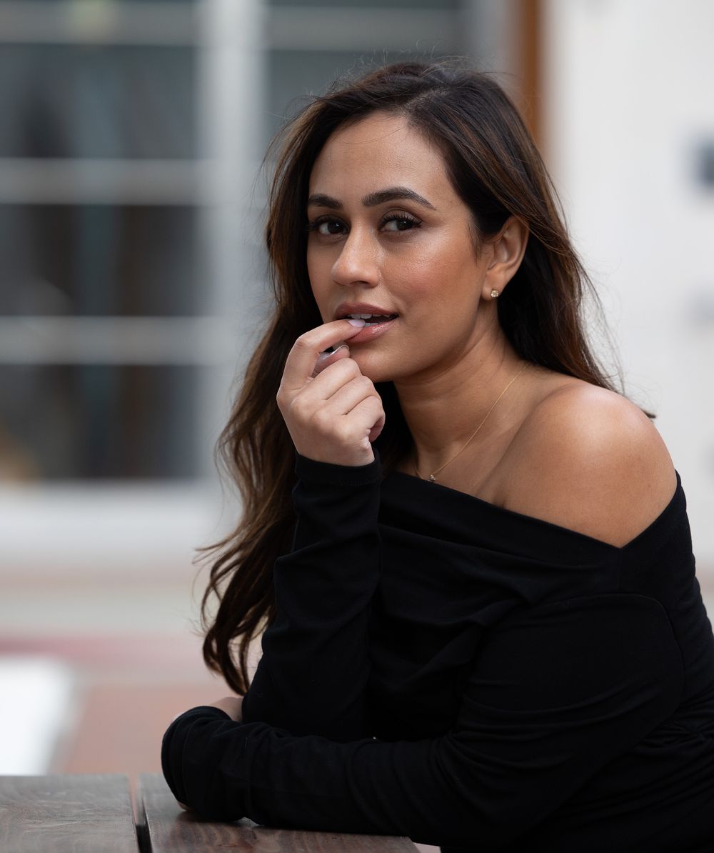 Portrait in casual black off-shoulder sweater with natural lighting and soft expression.