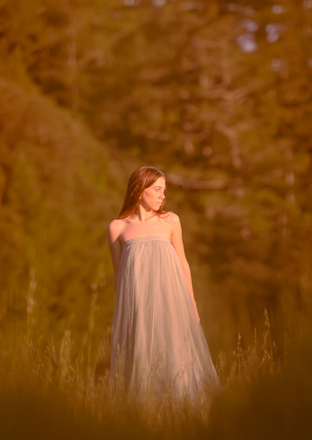 Figure in ethereal white dress standing in sunlit meadow.
