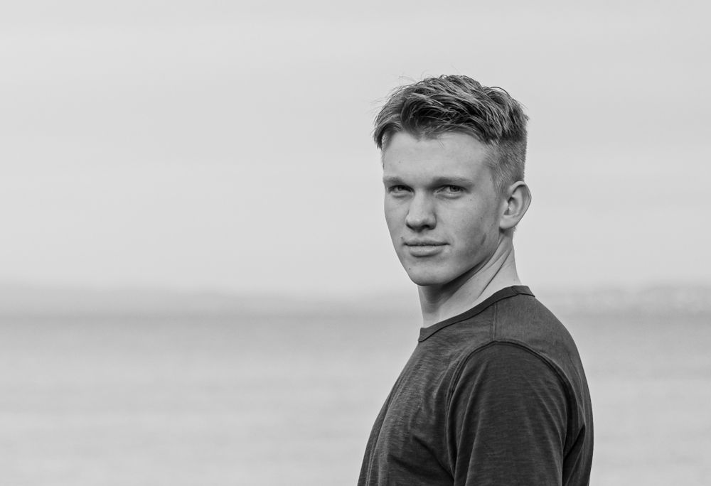 Black and white close-up portrait showing a casual expression against a blurred backdrop.