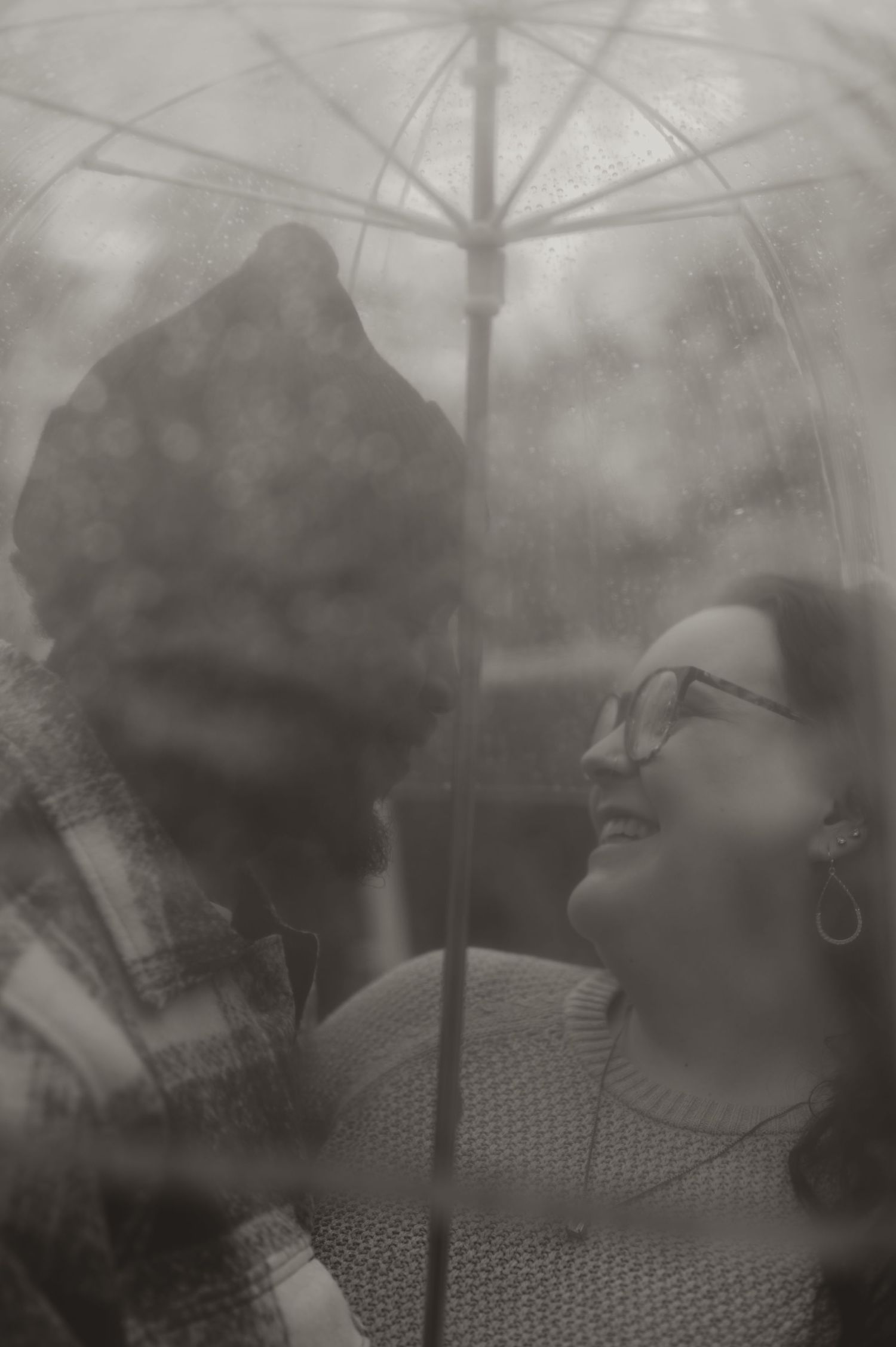 A romantic black and white photo by Samantha Campbell imagery of a couple sharing an intimate moment under an umbrella.