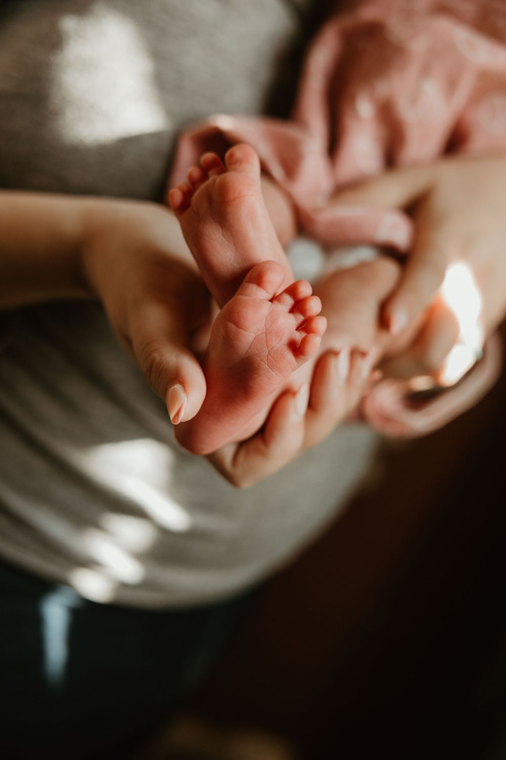 Tiny newborn feet being gently cradled in caring hands.