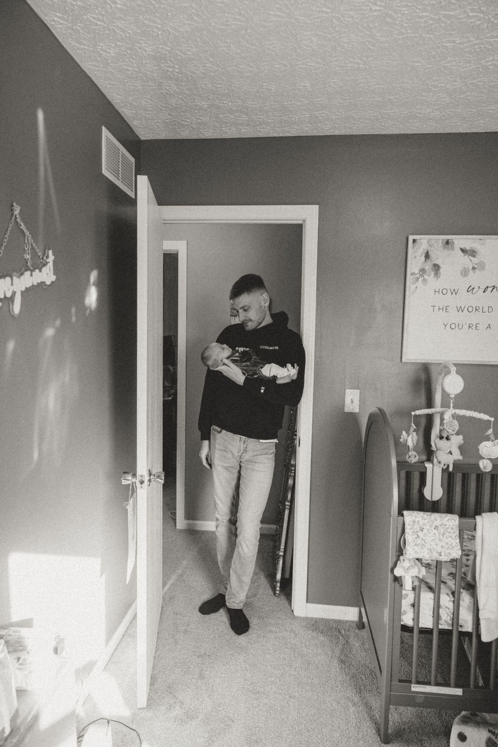 A cozy nursery corner with grey walls and baby items visible.