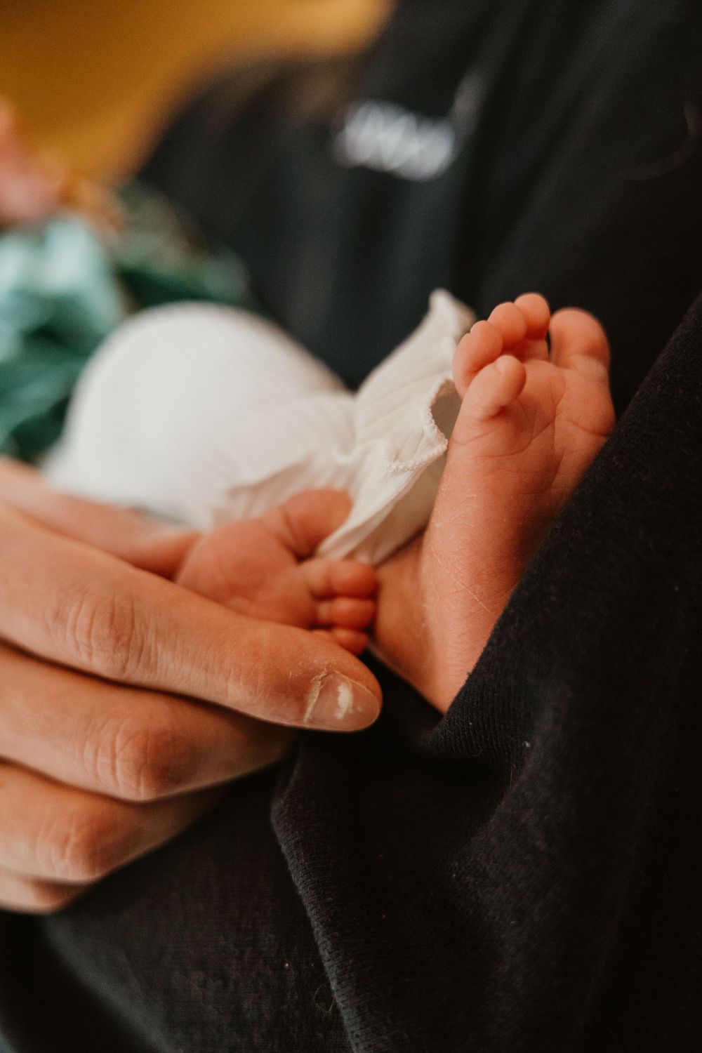 Close-up of tiny baby feet being held by gentle hands.