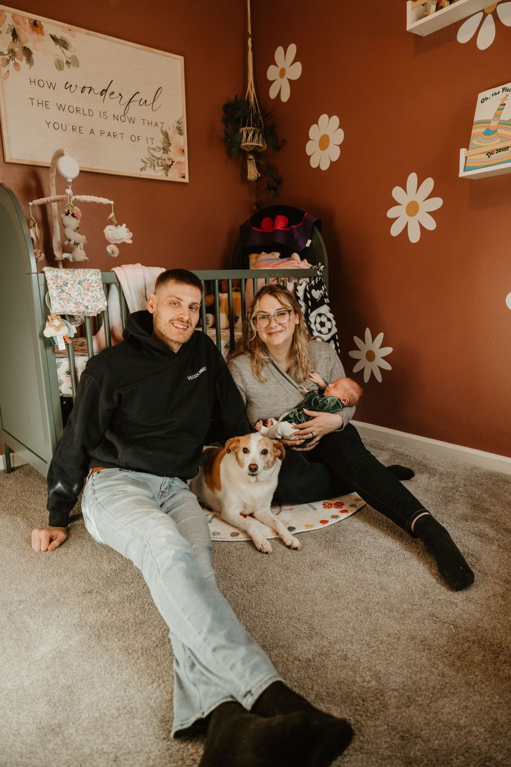 A nursery room with white daisy decals and a dog sitting on the carpet.