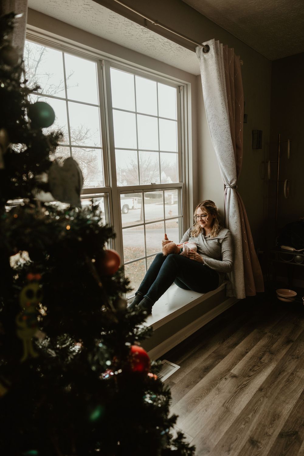 A cozy window seat scene with a Christmas tree in the foreground.