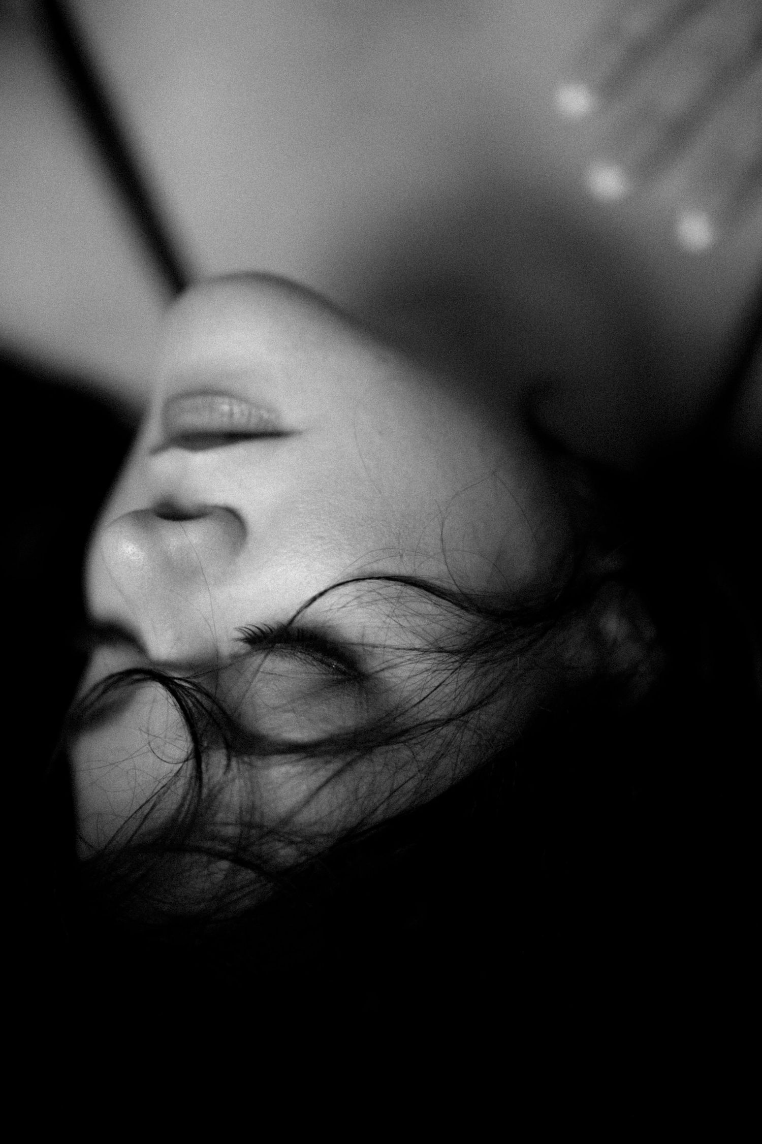 Close-up black and white profile portrait showing soft facial features and flowing hair.