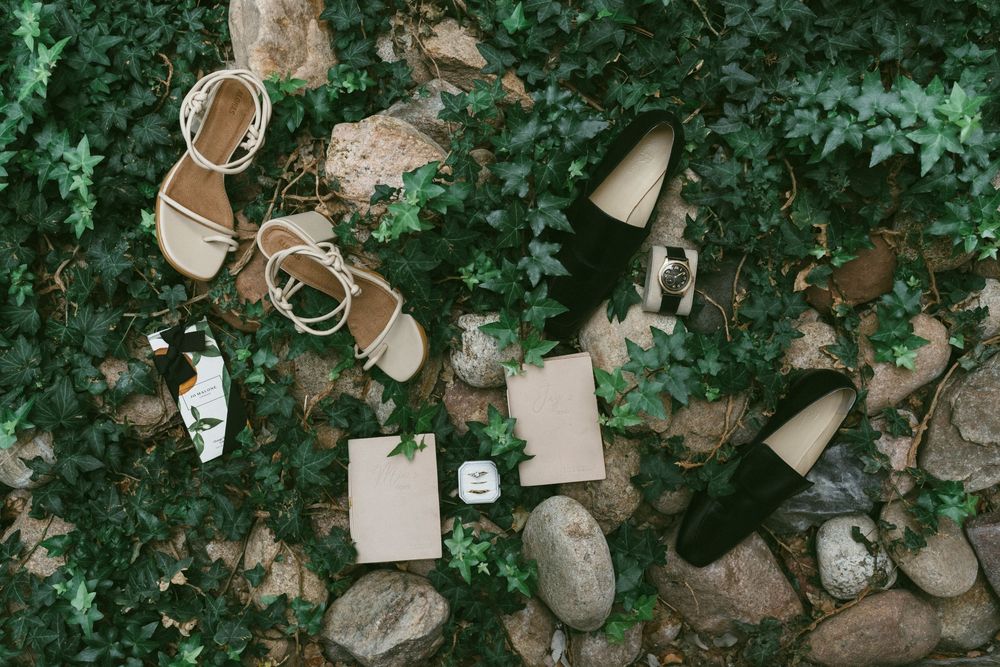 Wedding accessories including sandals, jewelry, perfume bottles, and decor items arranged on a green leafy background at Villa Parker