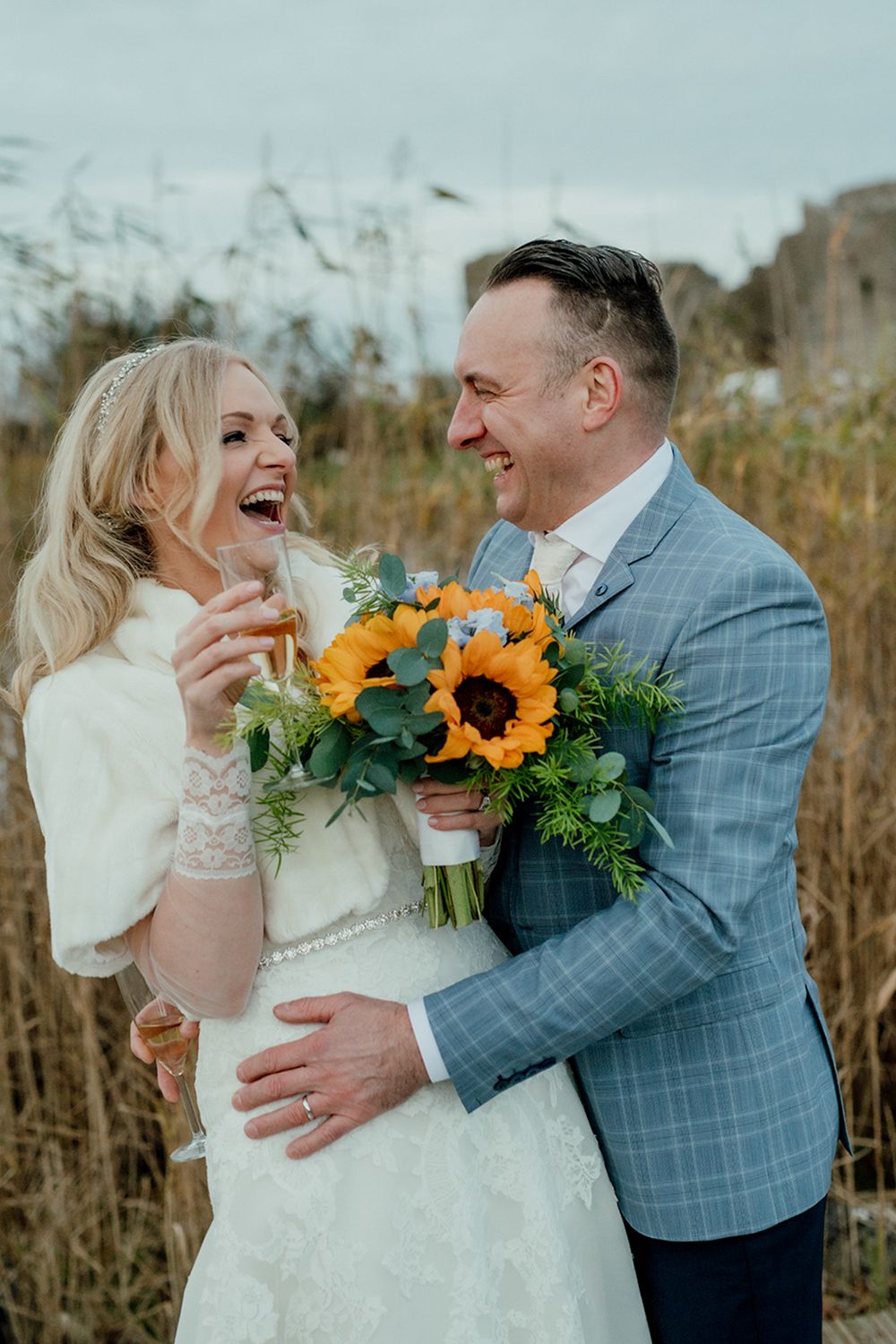 A newlywed couple sharing a laugh on their wedding day. Their genuine happiness is evident as they celebrate against a rustic outdoor.