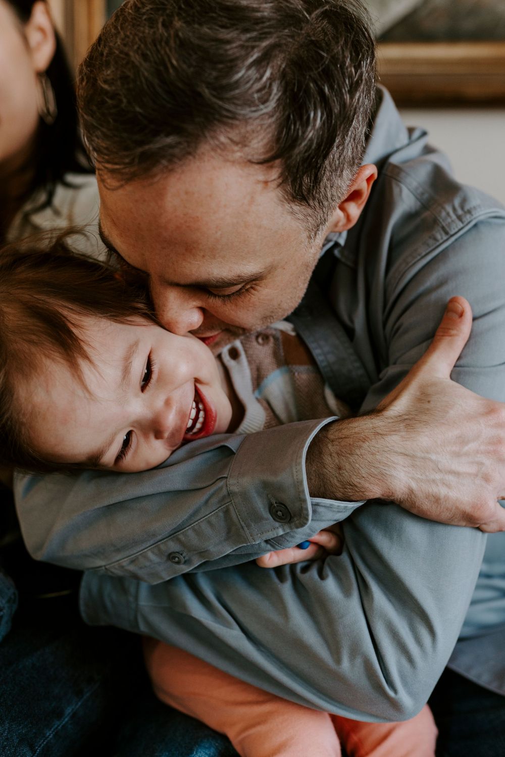 Family photography showing a tender moment of dad embracing and laughing with his child.