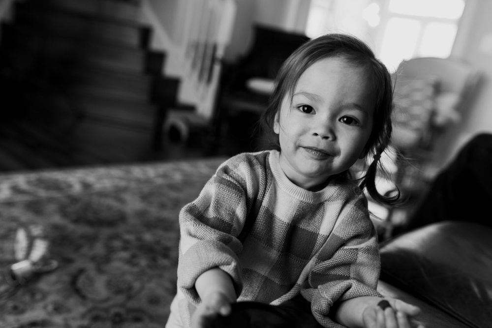 Black and white photo portrait of a small child in-home in their playroom.