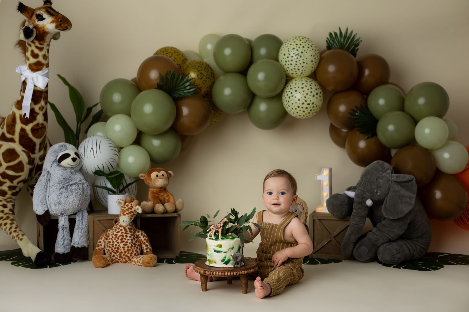Baby boy sitting in a custom theme jungle background for his studio cake smash portrait session.