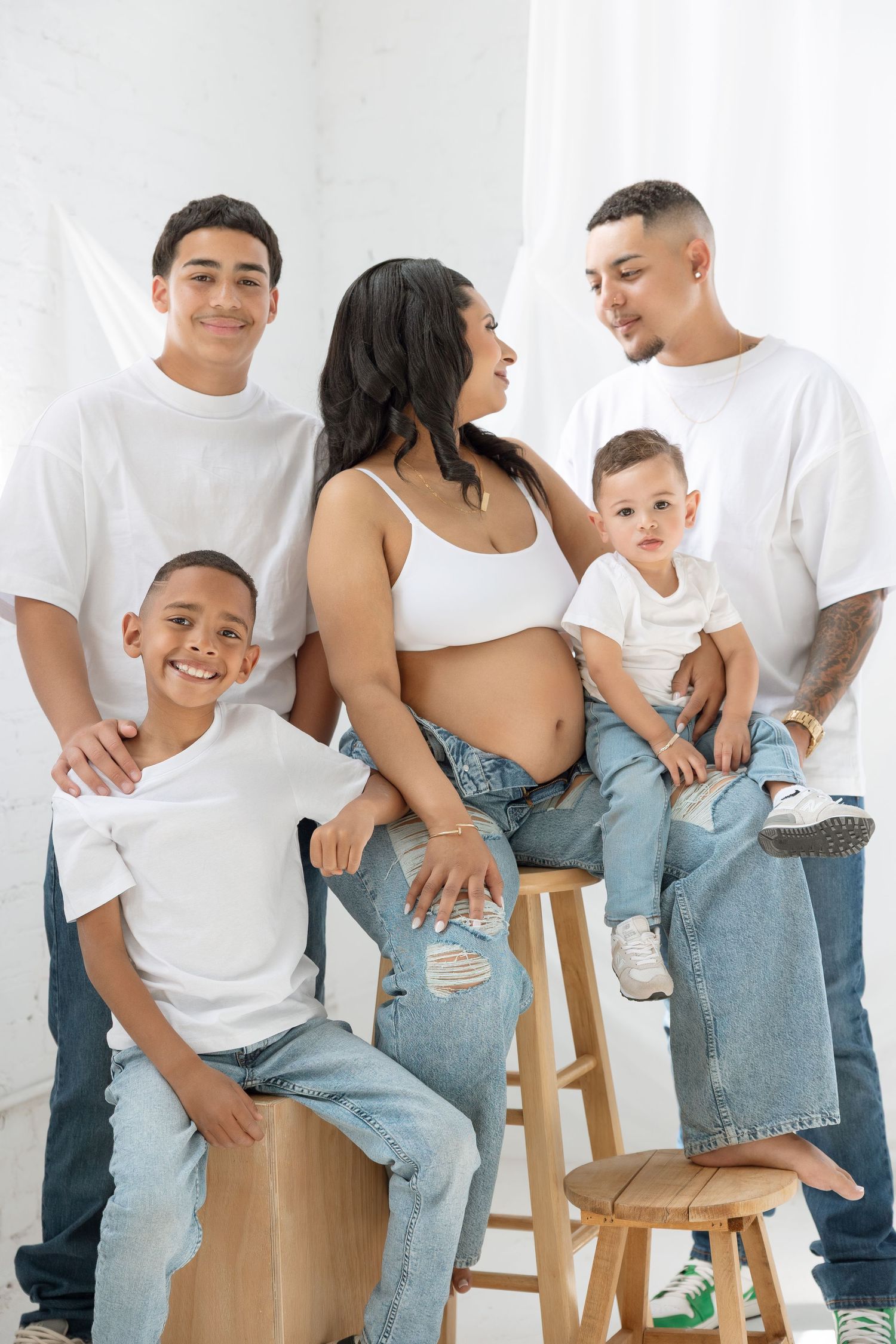 A joyful group poses together in a casual studio setting wearing white and black clothing.