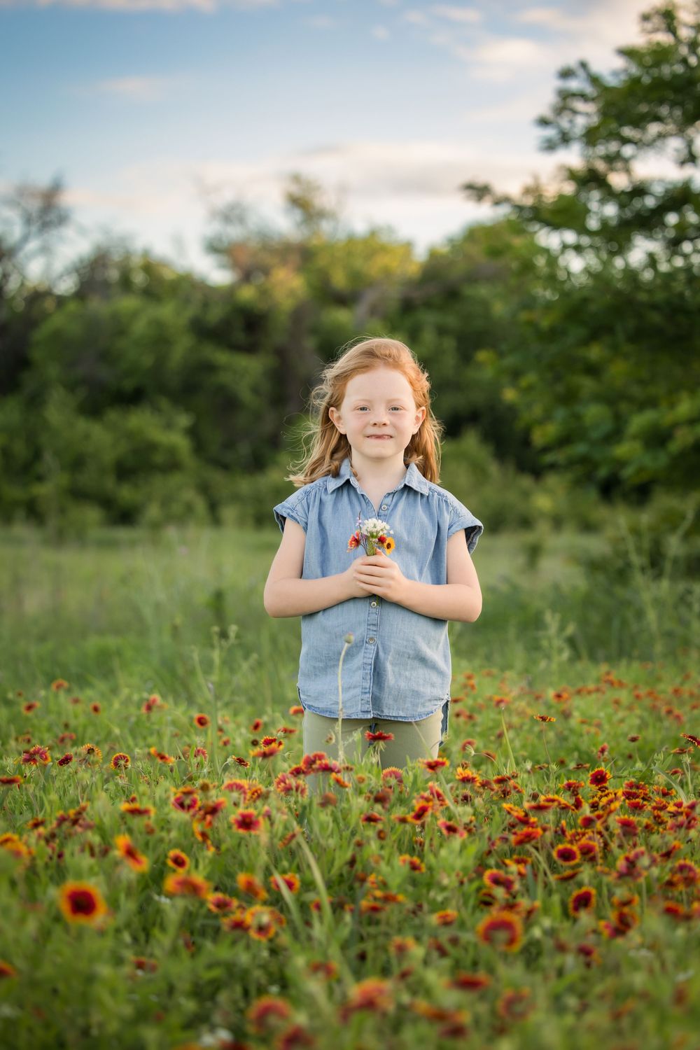 Young child stands in a vibrant meadow filled with orange wildflowers on a sunny summer day.