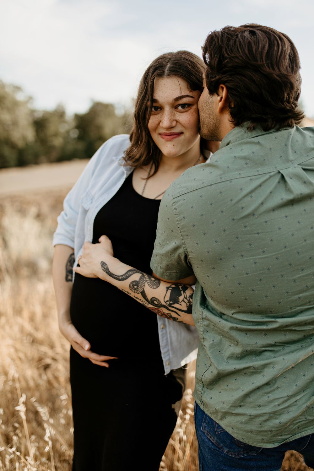 Loving couple embraces in a golden field at sunset during a maternity photoshoot in Shingle Springs.