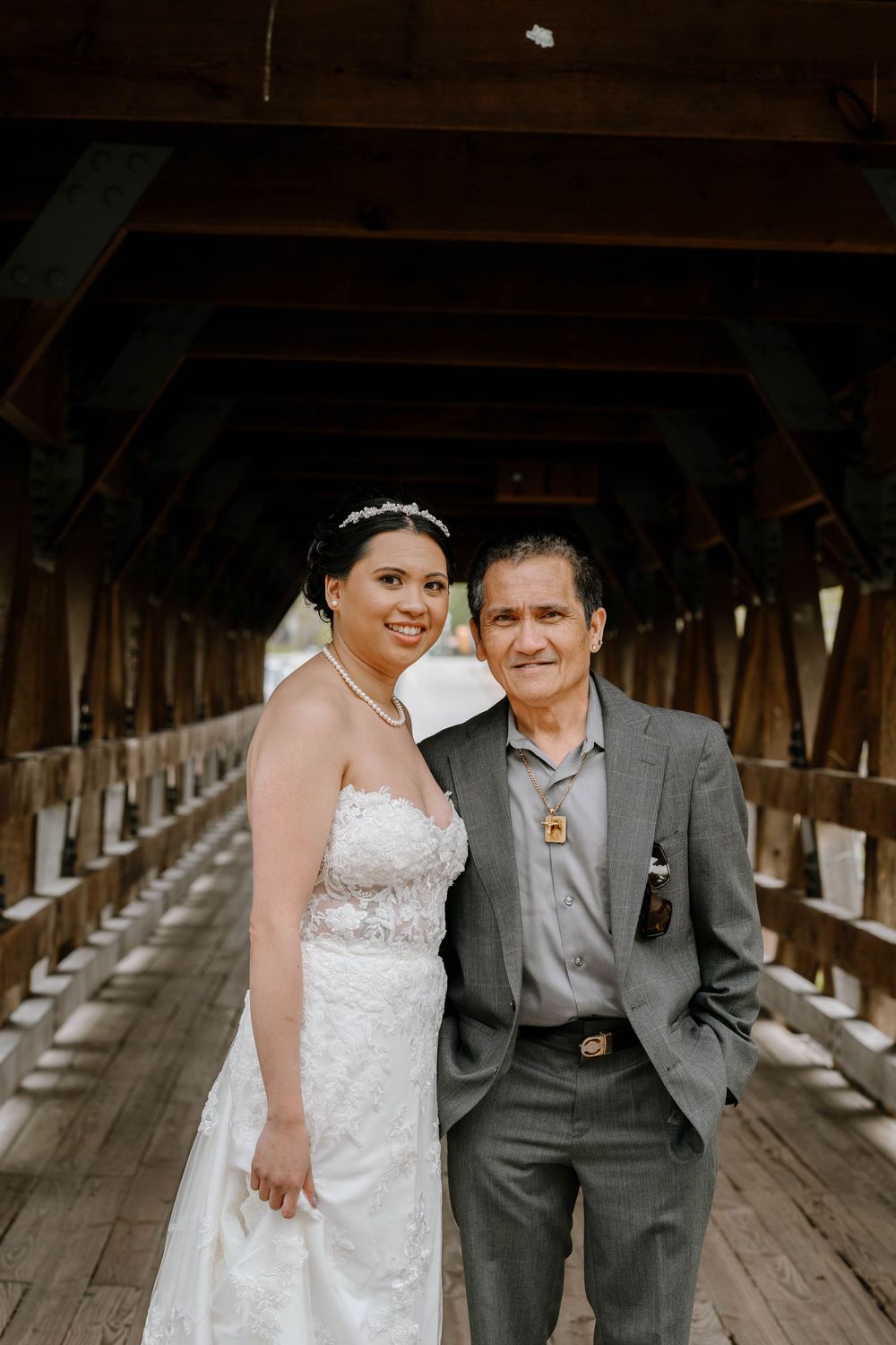 A wedding portrait taken inside a wooden covered bridge with natural lighting.