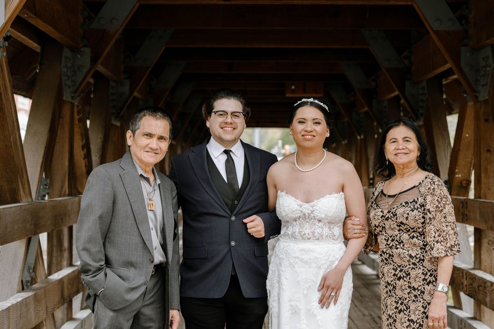 Formal wedding party portrait inside a rustic wooden covered bridge.