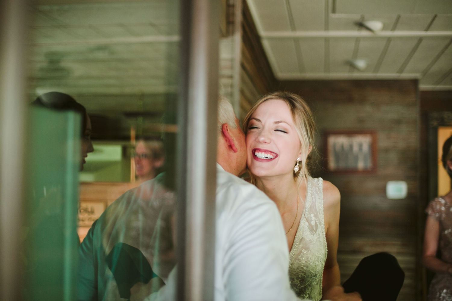 Joyful candid moment during wedding preparations in rustic cabin setting.