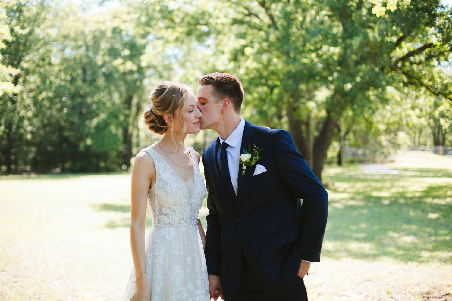 Romantic wedding portrait of couple in summer garden with soft natural lighting.