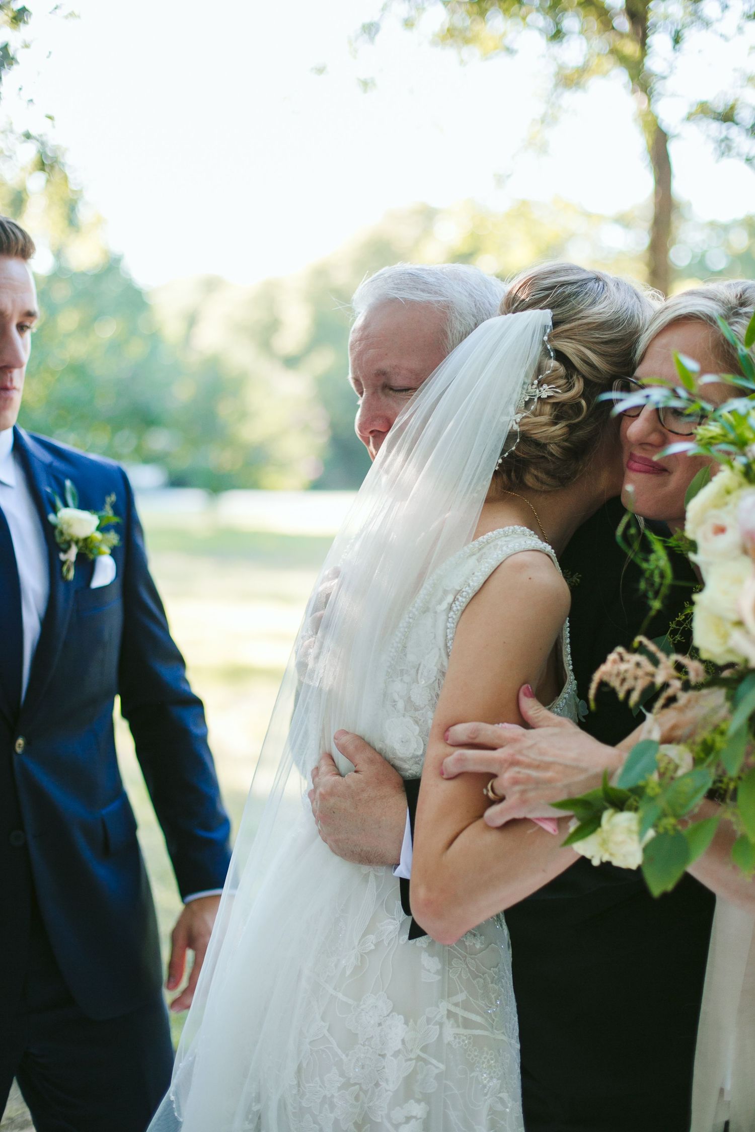 Tender moment shared between family members during outdoor wedding reception.