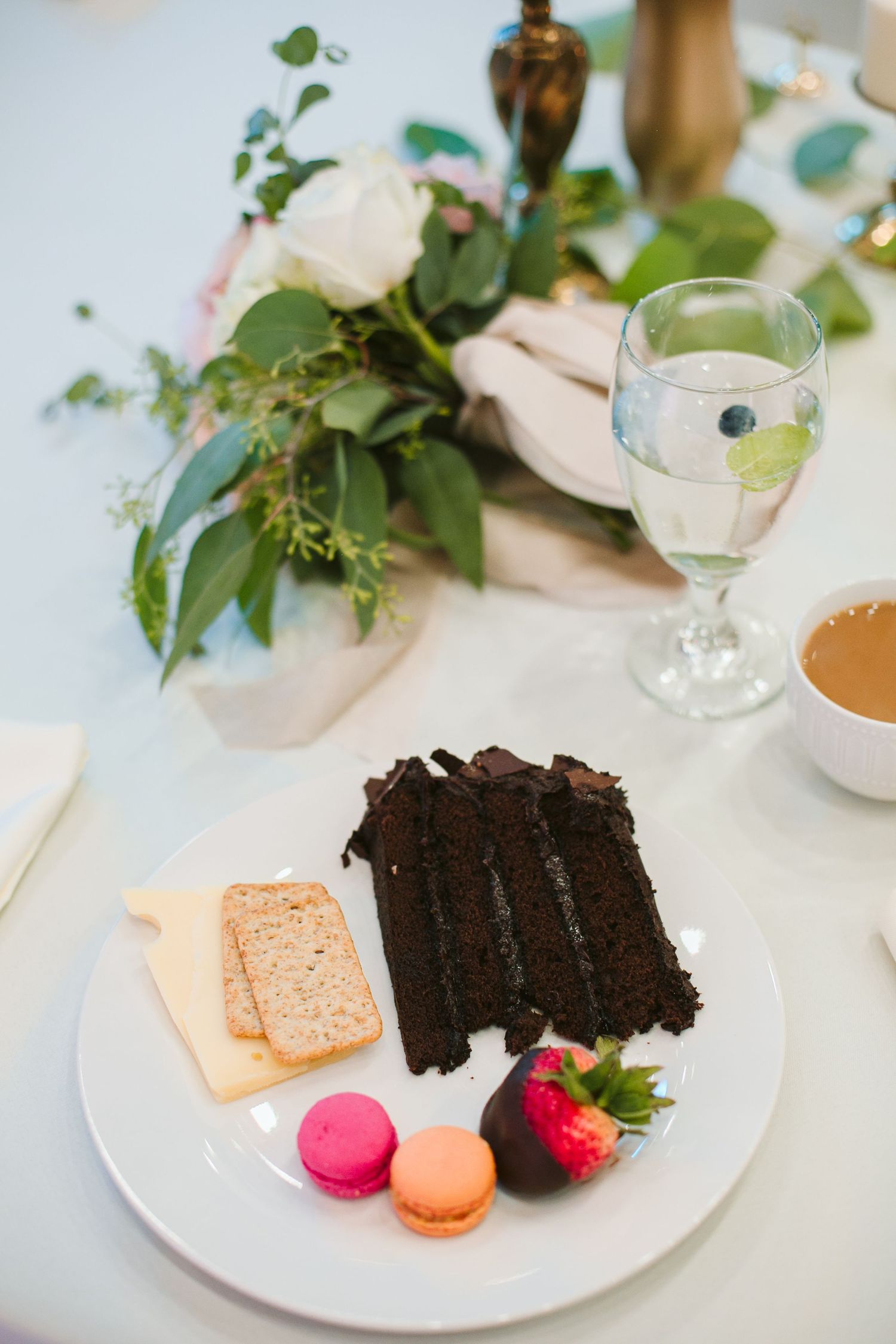 Wedding reception place setting with chocolate cake slice, macarons and floral centerpiece.