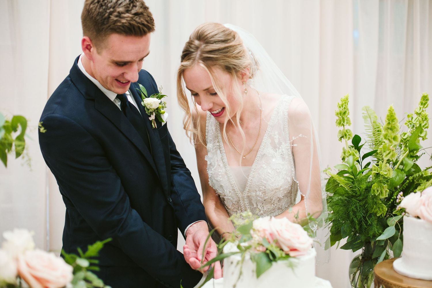 Intimate moment of couple cutting their wedding cake together.