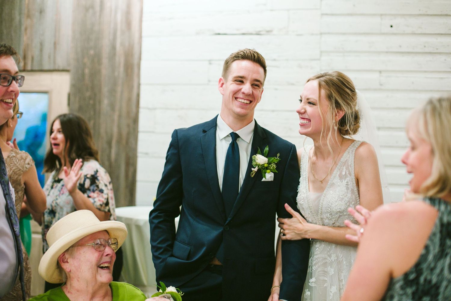 Candid reception moment with guests gathered in modern white-walled venue.