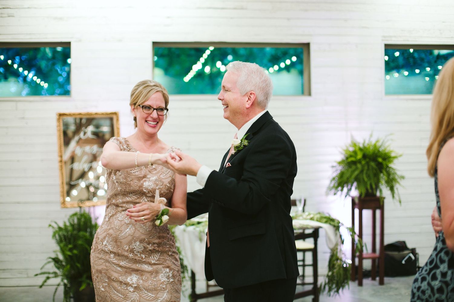 Dance floor celebration with guests enjoying wedding reception in white interior.