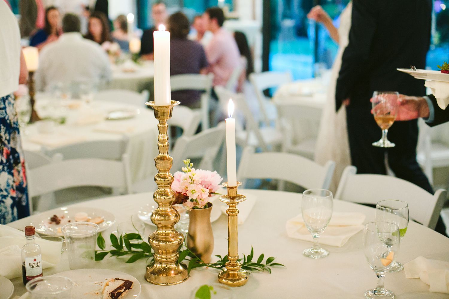 Elegant table setting with gold candlesticks and pink floral centerpieces at wedding reception.
