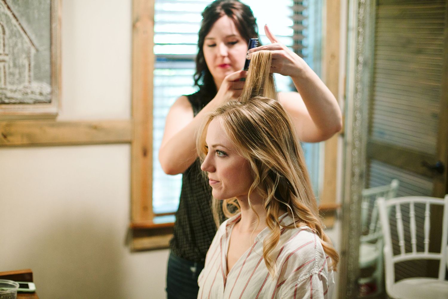 Wedding preparation moment in natural window light with wooden decor.