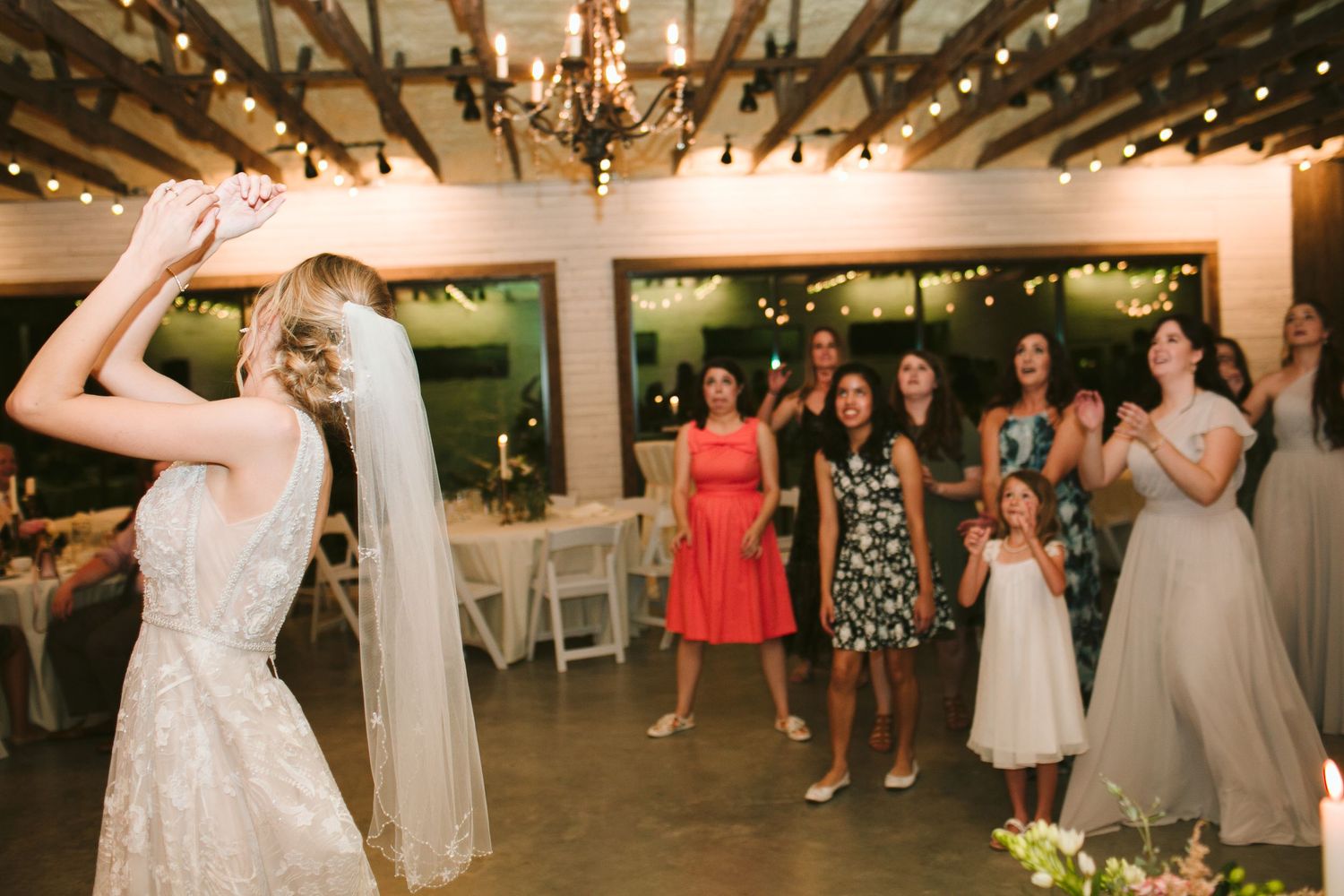 Wedding celebration in a rustic venue with string lights as guests dance during the reception.