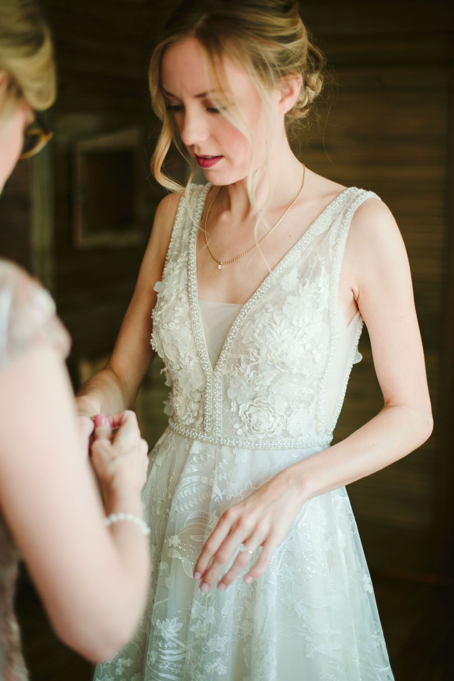 Elegant white lace wedding dress with delicate beading and v-neckline shown during bridal preparations.