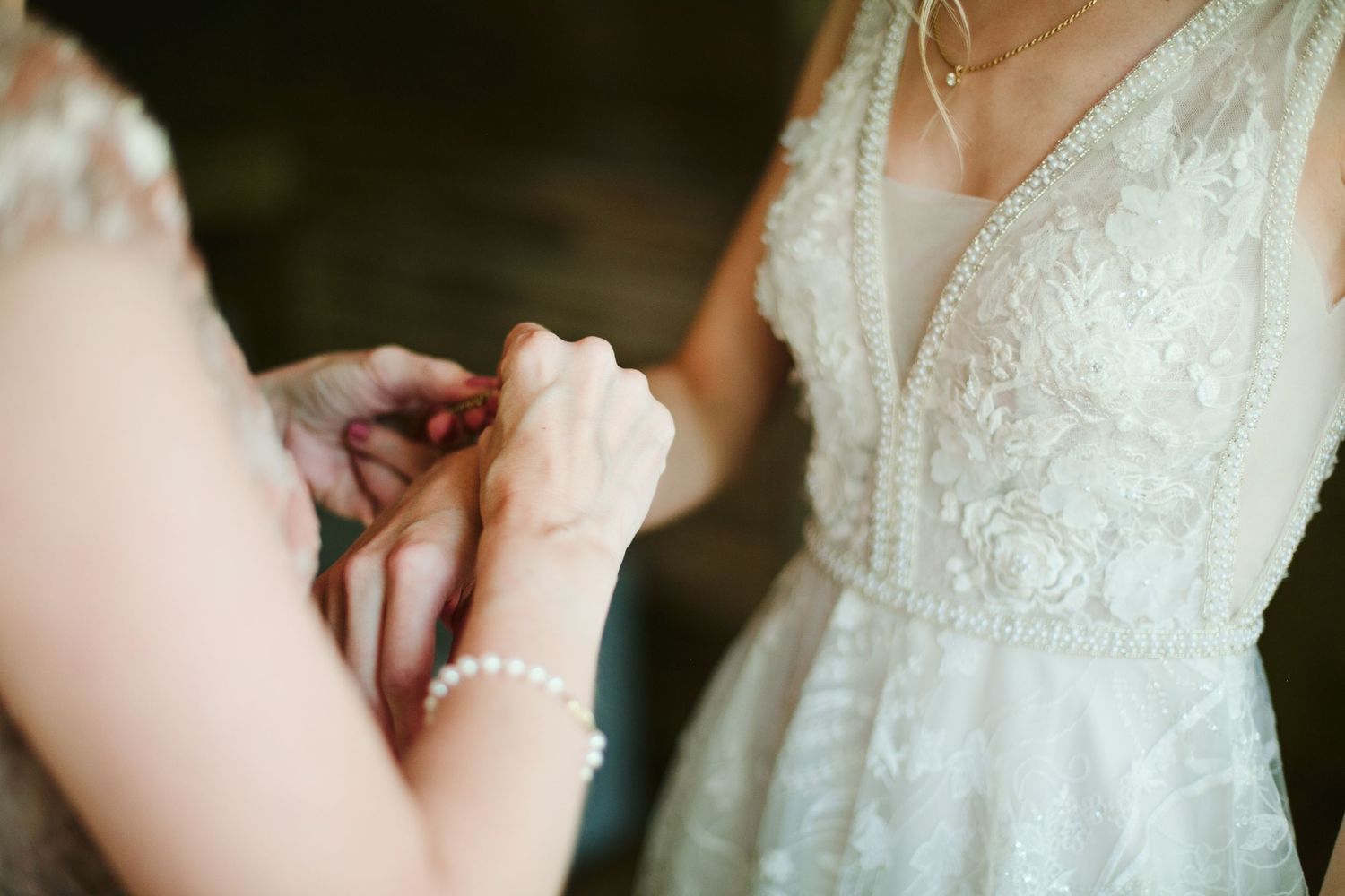 Close-up detail of bride's wedding dress bodice with intricate lace and beadwork.