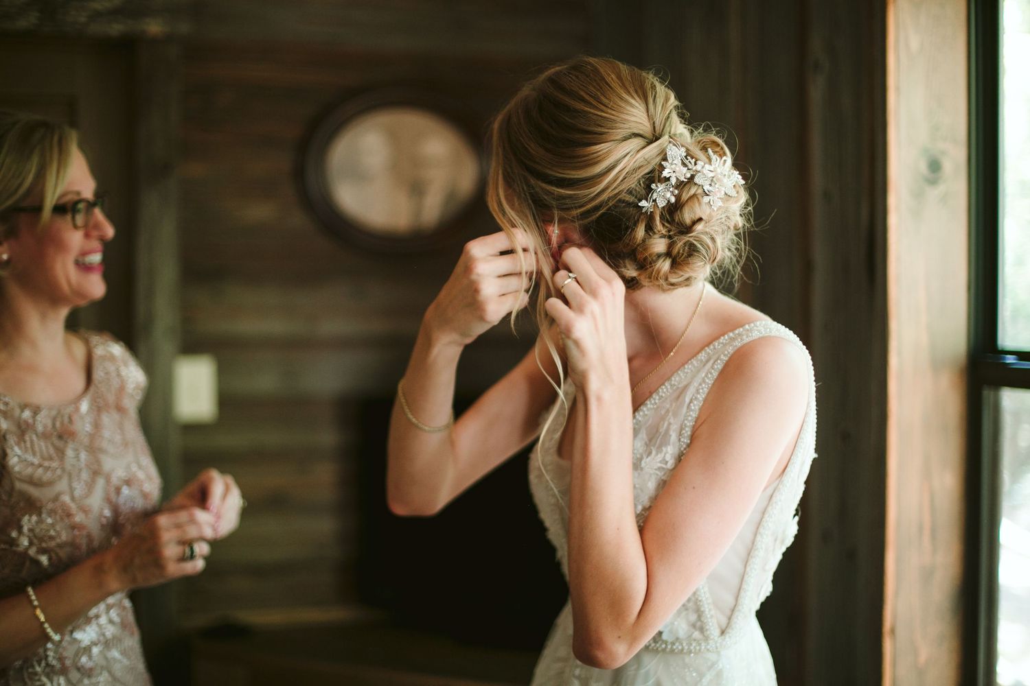 Getting ready moment in rustic cabin as finishing touches are added to bridal accessories.