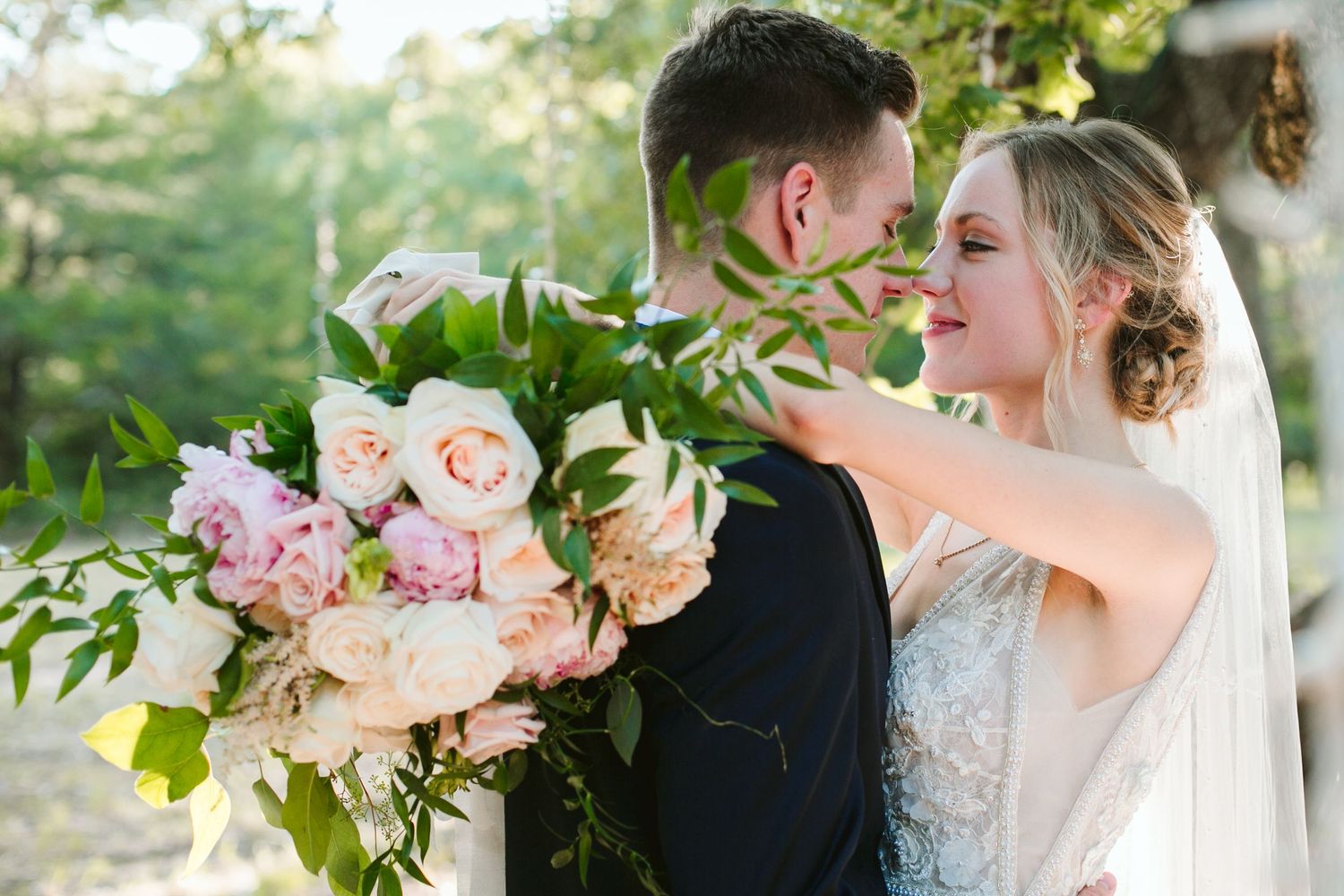 Close up of a romantic moment with pink roses and eucalyptus bouquet in sunlight.
